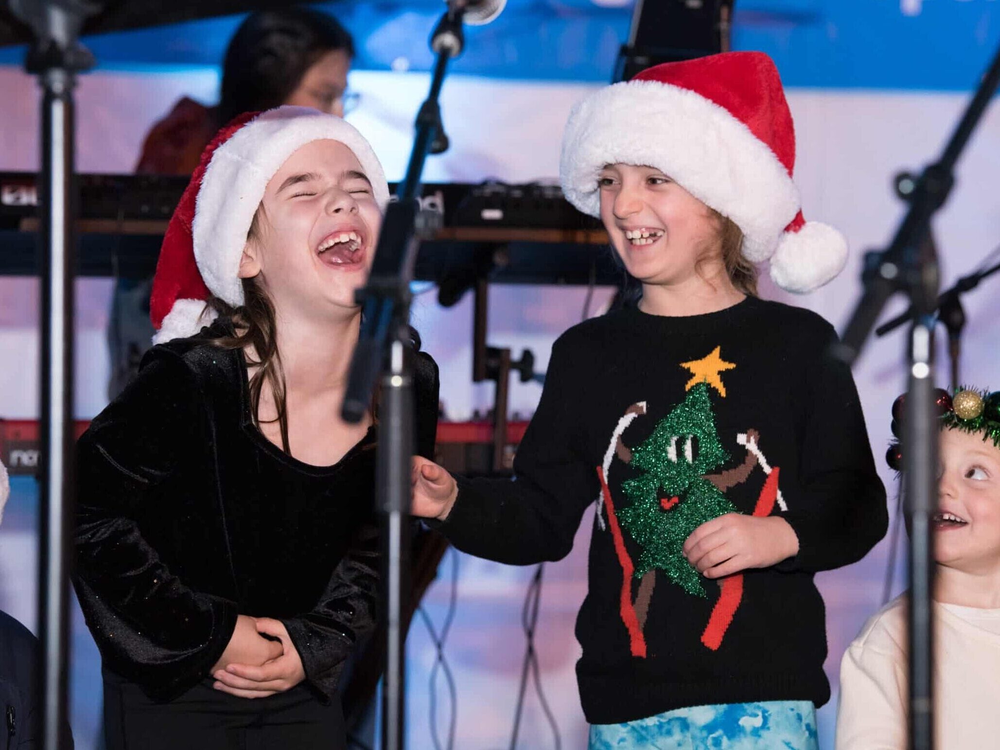 Two children in the West End Children's Choir laugh at a community performance.