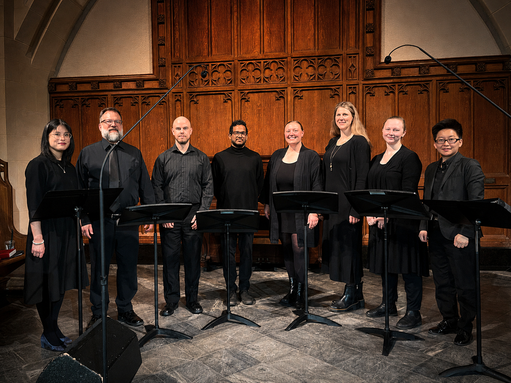 The Sacred Voices Ensemble at St. Andrew's-Wesley United Church in downtown, West End Vancouver, poses in a line in the church chancel. Pictured from left to right, Angelique Po, Music Director/Pianist/Organist; Derrick Christian, Bass; Chris Doughty, Bass; Asitha Tennekoon, Tenor; Tabitha Brasso-Ernst, Soprano; Rebecca Collett, Soprano; Magda How, Soprano; Peggy Hua, Conductor